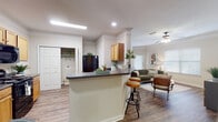 This well-appointed two-bedroom, two-bathroom residence in Memphis, Tennessee offers a thoughtfully designed single-floor layout that maximizes comfort and functionality. The open-concept kitchen is a central highlight, featuring warm wood cabinetry, dark granite-style countertops, a breakfast bar with bar seating, and black appliances including a refrigerator, range, and built-in microwave. The kitchen flows seamlessly into the living area, which is adorned with crown molding, a ceiling fan, and hardwood-style flooring that extends throughout the main living spaces. A dedicated dining nook provides an intimate space for meals. The living room is generously sized, offering room for a full seating arrangement and media setup. The primary bedroom features plush carpeting, crown molding, natural light from window treatments, and a spacious walk-in closet. The second bedroom is also carpeted and well-lit, with ample room for versatile use. Both bathrooms include a shower/tub combination, wood-tone vanity cabinetry, and hardwood-style flooring. A laundry closet with hookups adds everyday convenience. Throughout the home, neutral tones and consistent finishes create a cohesive, inviting ambiance.