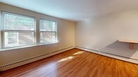 This single-floor unit at 3618 Colfax Ave S in Minneapolis offers a straightforward, functional layout spread across several distinct living areas. The flooring varies throughout the space, with warm hardwood floors found in the main living and kitchen areas, while plush carpeting covers at least one bedroom, providing a softer underfoot feel.

The kitchen is compact yet practical, equipped with a gas range, a full-sized refrigerator, and a dedicated counter area with a butcher block surface. Cabinetry is clean and white, extending to the ceiling for ample storage, and a mosaic tile backsplash adds a subtle design detail above the stainless steel sink. Track lighting illuminates the kitchen efficiently.

The living areas include rooms with natural light filtering in through multiple windows, offering views of the surrounding neighborhood greenery. Baseboard heating runs along the walls throughout the unit. One room features a ceiling fan with a built-in light fixture, adding both ventilation and ambient lighting.

The bathroom retains a retro character with pink ceramic tile lining the walls of the tub surround and continuing partway up the surrounding walls, complemented by a pedestal-style sink and a medicine cabinet mirror. The overall ambiance of the unit is modest and functional, suited for straightforward, comfortable day-to-day living.