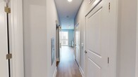 Located at 940 E Adams St in Jacksonville, Florida, this single-floor unit offers a thoughtfully designed layout that maximizes functionality and comfort. The open-concept living and kitchen area is highlighted by warm light hardwood flooring, creating a bright and welcoming atmosphere. The modern kitchen is a standout feature, equipped with sleek white cabinetry, a classic subway tile backsplash, stainless steel appliances including a refrigerator, range, microwave, and dishwasher, and a single-basin sink. Track lighting overhead ensures the space is well-lit, while large windows allow natural light to filter in. A ceiling fan is centrally positioned in the main living area, promoting comfortable airflow throughout. The bedroom is finished with soft wall-to-wall carpeting underfoot and features its own ceiling fan, a sliding closet door for efficient space use, and windows fitted with blinds for privacy and light control. Neutral gray-toned walls throughout the unit lend a clean, contemporary aesthetic that pairs well with the varied flooring materials. A hallway connects the main living areas, contributing to a smooth and practical flow within the space.
