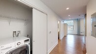 This thoughtfully laid-out 1-bedroom, 1-bathroom residence makes excellent use of its single-floor footprint, offering a clean, modern aesthetic throughout. Warm wood-style flooring flows continuously across all living areas, complemented by crisp white walls and recessed lighting that keep the space feeling bright and open.

The kitchen is well-appointed with stainless steel appliances, including a full-size refrigerator, gas range, built-in microwave, and dishwasher. White cabinetry and dark countertops provide a contemporary contrast, while ample counter space supports everyday functionality.

A central hallway connects the living areas to the private spaces, with convenient in-unit laundry tucked behind a sliding door — a practical and space-conscious design choice. The hallway also leads to the full bathroom, which features wood-style flooring consistent with the rest of the unit and clean, neutral finishes.

The bedroom is a standout feature, boasting soaring ceilings with exposed structural elements and large windows that invite natural light and offer views of the surrounding brick exterior. A sliding-door closet with built-in wire shelving provides organized storage. The overall ambiance of the space is modern and minimalist, ideal for those who value clean design and efficient living.