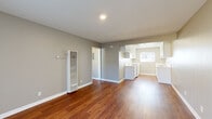 This single-story residence offers a compact yet efficient living space of 710 square feet. The home features four bedrooms, including a primary bedroom of 150 square feet, alongside one bathroom. The layout encompasses a living room, kitchen, and hallway, all interconnected on a single floor.

The interior is characterized by a modern aesthetic, with neutral-toned walls complementing rich, warm hardwood flooring that runs consistently throughout the space. The living area is notably spacious, featuring recessed lighting and a wall-mounted heating unit for comfort. Large windows and a glass door in this area allow for ample natural light, enhancing the sense of openness.

The kitchen, while compact, boasts a contemporary design with crisp white cabinetry, light-colored countertops, and stainless steel appliances. It includes a window above the sink, providing natural light and ventilation. The galley-style layout maximizes efficiency in the limited space.

Bedrooms are modest in size but well-lit, with some featuring windows that offer outdoor views. The bathroom, though not expansive, is functional and features a combined tub and shower unit with white tiling for a clean, bright appearance.

Overall, this home presents a well-designed, low-maintenance living option, ideal for those seeking a balance of functionality and modern comfort in a compact footprint.