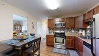 Located at 4543 Camp Rd in Hamburg, NY, this well-appointed single-floor residence offers a thoughtfully designed layout with two bedrooms and one full bathroom. The open-concept kitchen and living area serves as the heart of the home, featuring rich warm-toned cabinetry, a mosaic tile backsplash, stainless steel appliances including a gas range, built-in microwave, dishwasher, and refrigerator, all complemented by light hardwood-style flooring. A dining area sits adjacent to the kitchen, providing a seamless flow for everyday living and entertaining. The living room is carpeted and bright, highlighted by a sliding glass door with vertical blinds that fills the space with natural light and provides outdoor access. Both bedrooms are carpeted and offer a comfortable, neutral atmosphere. The primary bedroom is generously sized, featuring a double closet and a large window that invites natural light. The second bedroom is well-proportioned with its own window. The full bathroom is finished with large-format tile flooring, warm neutral walls, a wood-toned vanity with a granite-style countertop, and a spacious walk-in shower/tub area. Throughout the home, clean lines, neutral tones, and practical finishes create a welcoming and functional living environment.
