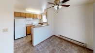 Located at 8615 83rd St Ct SW in Lakewood, Washington, this single-floor unit offers a well-organized layout designed for comfortable everyday living. The living area is generously sized, featuring warm neutral carpet, a classic brick-surround fireplace, and a sliding glass door that provides access to an outdoor space while allowing natural light to fill the room. Baseboard heating is present throughout, ensuring year-round comfort.

The kitchen is designed with functionality in mind, showcasing warm wood-toned cabinetry, laminate countertops, and a breakfast bar peninsula that separates the kitchen from the adjacent dining area. White appliances including a refrigerator, range, and microwave are included. A ceiling fan overhead adds airflow to the combined kitchen and dining space, which features durable tile flooring that extends into the bathroom areas.

The bedrooms are carpeted and well-proportioned, each offering closet storage. One bedroom connects directly to a private bathroom with wood-accented cabinetry, a vanity with mirror, and tile flooring, while an additional bathroom serves the rest of the unit with a similar clean, functional design. Additional bedrooms feature natural light through windows with blinds. The overall ambiance is clean, neutral, and move-in ready.