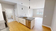 This contemporary 610 square foot apartment offers a harmonious blend of style and functionality. The heart of the home is an open-concept kitchen and living area, showcasing a sleek design with white cabinetry, stainless steel appliances, and a subway tile backsplash. The kitchen island, topped with a gray countertep, provides additional workspace and casual dining options.

The living room seamlessly connects to the kitchen, creating an ideal space for entertaining or relaxation. Large windows flood the area with natural light, enhancing the sense of spaciousness. The bedroom, measuring 140 square feet, offers ample space for a comfortable retreat, complete with a window for natural illumination and ventilation.

The bathroom features modern fixtures, including a vanity with a marble countertop and a glass-enclosed shower. Throughout the apartment, light-colored walls and warm wood-tone flooring create a bright and inviting atmosphere. A dedicated closet space ensures practical storage solutions.

This single-floor layout maximizes efficiency and ease of movement. The property's location at 150 Broad Street in Windsor, CT, adds to its appeal, offering a blend of urban convenience and suburban comfort.