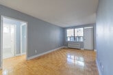 Located at 35 Spencer Ave in Toronto's vibrant Parkdale neighbourhood, this one-bedroom, one-bathroom unit offers a well-organized layout across a single floor. Warm-toned parquet flooring flows throughout the living spaces, adding timeless character to the soft grey-painted walls.

The combined kitchen and living area is thoughtfully divided. The galley-style kitchen features crisp white shaker cabinetry with brushed nickel hardware, white quartz countertops, a stainless steel refrigerator, and a gas range — offering ample storage and a clean, functional workspace. The adjoining living room is bright and open, with a large window and direct access to a private balcony, allowing for natural light and outdoor views.

The bedroom is a comfortable size, featuring a built-in sliding closet, a window with natural light, and the same polished parquet flooring seen throughout. Radiator heating units are present in both the living room and bedroom, characteristic of the building's classic construction.

The bathroom is finished in clean white tile, complete with a full soaker tub and a window above, providing ventilation and natural light. A dedicated entrance area completes this practical and well-maintained unit, making it a solid choice in central Toronto.