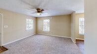 Located at 2436 Beach Blvd in Biloxi, Mississippi, this two-story unit offers 3 bedrooms and 3 bathrooms arranged across two distinct floors. The lower level is more compact, housing the kitchen and living areas, while the upper floor provides the majority of the living space, including all three bedrooms and connecting hallways.

The kitchen features dark wood cabinetry, wood-look vinyl flooring, and white appliances including a refrigerator, range, and dishwasher. A textured ceiling and fluorescent lighting give the kitchen a functional, utilitarian feel. The living room is carpeted and receives natural light through windows and a sliding glass door fitted with vertical blinds, providing outdoor access.

Upstairs, the three bedrooms are finished with neutral beige walls and plush carpeting. The generously sized primary bedroom includes dual closets and a ceiling fan, while the secondary bedrooms feature large windows that allow ample natural light. Each bedroom offers a calm, understated aesthetic. The three bathrooms include tub-shower combinations with wood-look flooring and vanities with undermount sinks, maintaining a consistent, straightforward design throughout the home.