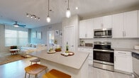 Located at 5240 Bridge St in Tampa, Florida, this single-floor residence presents a thoughtfully designed interior with a contemporary aesthetic throughout. The open-concept kitchen serves as a central highlight, featuring white shaker cabinetry, quartz countertops, subway tile backsplash, and a full suite of stainless steel appliances including a range, microwave, and dishwasher. A large center island with bar seating provides additional prep space and a casual dining option, illuminated by stylish pendant lighting overhead. Light wood-look tile flooring flows seamlessly through the kitchen and main living areas, creating a cohesive and airy feel.

The living room is bright and welcoming, with multiple windows and a glass-paned door that invite natural light, complemented by a ceiling fan overhead. The bedroom offers plush carpeting, a large window, and ample space for a full-size furniture arrangement. Two well-appointed bathrooms feature white cabinetry, framed mirrors, neutral countertops, and wood-look tile flooring. One bathroom includes a glass-enclosed walk-in shower with marble-style tile walls. A dedicated laundry area with full-size washer and dryer connections adds practical convenience to this polished, move-in-ready residence.