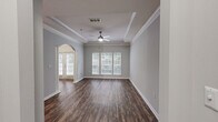 Located at 5375 Sugarloaf Pkwy in Lawrenceville, GA, this thoughtfully designed one-bedroom, one-bathroom residence offers a comfortable and stylish living experience across a single floor. The inviting living room features rich hardwood-style flooring, a tray ceiling with crown molding, a ceiling fan, and large windows that fill the space with natural light. A distinctive arched entryway with decorative columns connects the living area to the entrance, adding an elegant architectural touch. The kitchen is a standout, boasting rich cherry wood cabinetry, granite countertops, a sage green subway tile backsplash, stainless steel appliances, and a central island — ideal for both cooking and entertaining. The carpeted bedroom is generously sized, bathed in natural light from a large window, and equipped with a ceiling fan and a spacious walk-in closet with wire shelving for ample storage. The bathroom features a granite-topped white vanity, a large mirror, and hardwood-style flooring. A dedicated in-unit laundry room with a full-size washer and dryer adds everyday convenience. Neutral gray walls and consistent finishes throughout lend the space a clean, cohesive aesthetic.