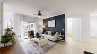 This thoughtfully designed 2-bedroom, 1-bathroom residence spans a single floor and offers a cohesive blend of modern style and functional living. The open-concept living room serves as the heart of the home, featuring light hardwood flooring, crown molding, a ceiling fan, and a striking dark accent wall that creates a bold focal point. A sliding glass door floods the space with natural light and provides direct access to a private balcony. The adjacent dining area benefits from large windows dressed in dark drapery, while the kitchen is outfitted with white shaker cabinetry, granite countertops, stainless steel appliances, and a breakfast bar with bar seating. Both bedrooms are carpeted and well-proportioned, with the spacious primary bedroom offering generous room for furnishings. The full bathroom features tile flooring, a granite-topped vanity with white cabinetry, a glass-enclosed shower, a soaking tub, and access to a walk-in closet. A dedicated laundry room with full-size washer and dryer hookups and built-in shelving adds everyday convenience. Throughout the residence, a neutral color palette and consistent finishes contribute to a clean, contemporary ambiance.