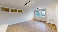 This contemporary 1-bedroom apartment, known as the I2 Floor Plan, offers 1020 square feet of thoughtfully designed living space. The open-concept layout seamlessly integrates the kitchen, living, and dining areas, creating a spacious and airy atmosphere. The kitchen boasts a modern aesthetic with crisp white upper cabinets contrasting beautifully with light wood lower cabinets. Stainless steel appliances, including a refrigerator, microwave, and range, complement the sleek design.

The living area features track lighting and large windows that flood the space with natural light. Light-toned wood-style flooring runs throughout, enhancing the bright and open feel. The bedroom, measuring 170 square feet, provides a cozy retreat with plush carpeting and ample space for a full bedroom set.

Two full bathrooms offer convenience and luxury, both featuring modern fixtures and finishes. One bathroom showcases a glass-enclosed shower, while the other includes additional storage space. The apartment also includes two closets for added storage.

The property's clean lines, neutral color palette, and contemporary fixtures create a sophisticated urban living experience. With its efficient use of space and high-quality finishes, this apartment is ideal for those seeking a modern, low-maintenance lifestyle in a prime location.