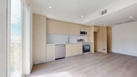 Located in the heart of Hollywood at 7050 Hawthorn Ave, Unit 406A, this modern 1-bedroom, 1-bathroom residence offers a thoughtfully designed layout with clean lines and contemporary finishes throughout. Light wood-tone flooring runs seamlessly across the open-concept living, dining, and kitchen area, creating a bright and cohesive atmosphere. The kitchen features floor-to-ceiling flat-front cabinetry in a warm natural wood finish, stainless steel appliances including a dishwasher, range, and built-in microwave, complemented by a sleek glass tile backsplash and a single-basin sink. Recessed lighting illuminates the space efficiently. The bedroom is a serene retreat with light hardwood flooring, clean white walls, a dedicated closet with built-in shelving, and a sliding glass door opening to a private balcony with outdoor views of the surrounding neighborhood and tree line. The bathroom is finished with large-format light tile flooring and walls, and includes a soaking tub with a glass-enclosed shower surround. Additional highlights include in-unit laundry, a hallway entry, and two closets for ample storage. The unit's minimal, modern aesthetic and efficient use of space make it a well-appointed urban residence.