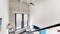 Located at 220 S 47th St in Philadelphia, PA, this multi-level unit offers a distinctive industrial loft aesthetic spread across three floors. The entry level features a galley-style kitchen with stainless steel appliances, dark tile flooring, and an open sightline to the living area, where a dramatic steel staircase with metal railing serves as a striking architectural centerpiece. Large windows flood the living space with natural light and provide city-facing views, complemented by soaring ceilings, exposed whitewashed brick walls, and an overhead ceiling fan.

The bedrooms are thoughtfully distributed across the floors, each carrying its own character. One bedroom showcases exposed ceiling beams, painted brick, and warm wood-tone furnishings, while another features bold mustard accent walls and vibrant artwork for a pop of personality. A third bedroom offers light wood flooring and a black-framed interior window that adds an architectural detail. Both bathrooms are clean and modern, finished with large-format light tiles and walk-in shower enclosures. One includes a dark wood vanity for added warmth. Multiple hallways and staircases connect the levels, creating a dynamic, layered living experience throughout this unique Philadelphia residence.