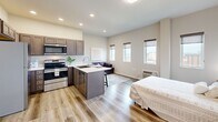 Located at 508 W 8th Ave in Spokane, Washington, Unit 7B is a thoughtfully designed one-bedroom, two-bathroom residence that maximizes every inch of its compact footprint. The open-concept layout seamlessly connects the kitchen, living, and sleeping areas, creating a cohesive and functional living space. Light wood-style flooring flows throughout, complementing the neutral, warm color palette of the walls and finishes.

The kitchen is a standout feature, equipped with stainless steel appliances including a refrigerator, range, microwave, and dishwasher. Rich, dark-toned cabinetry provides ample storage, while a peninsula with bar seating serves as both a workspace and casual dining area. Recessed lighting brightens the open area, which accommodates a living space alongside the sleeping area, making efficient use of the generous primary bedroom footprint.

A row of windows along the exterior wall invites natural light and offers views of the surrounding Spokane skyline. The bathroom is well-appointed with a dark wood vanity, white countertop, a large mirror, and a tiled tub-shower combination. A closet adds practical storage to round out this efficiently planned unit.