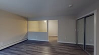 This two-floor residence offers a well-organized layout with distinct living spaces spread across both levels. The main floor features an open living area finished with dark, wide-plank hardwood flooring that lends a modern, grounded feel. A pass-through window connects the living area to an adjacent room, creating an open sightline that enhances the sense of space. Baseboard heating runs along the walls throughout the lower level. The galley-style kitchen is efficiently designed with white cabinetry, light granite-style countertops, a stainless steel sink, and black appliances including a gas range and refrigerator, all set on light wood-look flooring. A welcoming entryway on the main floor features a classic paneled front door and a staircase leading to the upper level. Upstairs, the bedrooms are finished with warm, rich hardwood flooring and are equipped with full-width mirrored sliding closet doors that amplify light and add a sense of depth. The bathroom is appointed with a dual-sink vanity topped with granite countertops, a large wall mirror, and a shower-tub combination. Neutral wall tones throughout the home create a clean, move-in-ready aesthetic that adapts easily to a variety of décor styles.