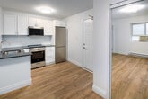 Located at 608 Church Street in Toronto's vibrant Church-Wellesley neighbourhood, unit A4 is a single-floor residence offering a thoughtfully updated interior with a clean, modern aesthetic throughout. The unit is finished with light hardwood-style flooring that runs through the main living and kitchen areas, complementing the bright white walls and creating a cohesive, contemporary feel.

The kitchen is a standout feature, outfitted with white shaker-style cabinetry providing ample upper and lower storage, dark charcoal countertops, and a white subway tile backsplash. A stainless steel undermount sink with a modern pull-down faucet anchors the counter space, while the kitchen is fully equipped with a stainless steel refrigerator, electric range, and an over-the-range microwave. The layout is efficient, with direct sightlines to the entry door for an open, connected feel.

The bedroom is a well-proportioned room with clean white walls, hardwood-style flooring, a ceiling light fixture, and a window fitted with a wall air conditioning unit. A baseboard heater runs along the wall, ensuring year-round comfort.

The bathroom features a fully tiled shower and tub combination with chrome fixtures, a white vanity with storage, and a bright, clean finish throughout.