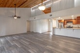 Located at 637 Olde Camelot Circle in Haines City, Florida, this single-story home showcases a striking architectural character defined by soaring vaulted ceilings clad in warm natural wood planking and exposed beams. The open-concept layout flows seamlessly from the entry through the expansive main living area, where large sliding glass doors fitted with vertical blinds invite abundant natural light and provide outdoor views. Ceiling fans are positioned throughout, complementing the airy, comfortable atmosphere.

The living space features light-toned wood-look flooring that extends through the main areas, adding warmth and continuity. A decorative pendant light anchors the open space, while clerestory windows near the ceiling peak enhance the sense of volume and brightness.

The kitchen is well-appointed with warm wood cabinetry, granite countertops, stainless steel appliances including a refrigerator and range, recessed lighting, and a generous peninsula that opens toward the living area—ideal for casual dining and entertaining. A decorative glass-panel entry door adds charm near the kitchen.

The bathroom features tile flooring, a tub-shower combination with full tile surround accented by a decorative border, a wood-toned vanity with granite countertop, and a large mirror. Additional rooms offer wood-look flooring, neutral walls, and access to adjoining spaces, including a walk-in closet area.