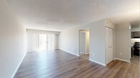 Located at 14000 Castle Blvd in Silver Spring, MD, this one-bedroom, one-bathroom residence offers a well-organized, single-floor layout designed for comfortable everyday living. The open living and dining area is finished with durable wood-style plank flooring and neutral gray walls, creating a bright, clean aesthetic throughout. A textured ceiling adds character, while large sliding glass doors dressed in vertical blinds flood the space with natural light and provide direct access to a private balcony with tree-lined outdoor views. The kitchen is outfitted with dark wood cabinetry, speckled stone countertops, and black appliances including a gas range and refrigerator, offering both functionality and a contemporary look. The generously sized primary bedroom features plush wall-to-wall carpeting and its own sliding glass door to an additional outdoor space, further enhancing the sense of openness. A dedicated hallway connects the main living areas to the bathroom, which includes a full tub-shower combination with clean white tile surround. The dining area and additional rooms continue the wood-style flooring found throughout the common spaces, ensuring a cohesive and polished finish across the entire residence.