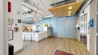 Located at 2363 E Evans Ave in Denver, CO, the University Lofts Lobby & Game Room is a generously sized, single-floor amenity space that blends industrial design with modern comfort. The open layout features exposed ductwork and piping along the soaring ceilings, polished concrete floors, and abundant natural light streaming through large floor-to-ceiling windows that offer views of the surrounding streetscape.

The lobby reception area is anchored by a sleek white front desk set against a bold blue accent wall displaying the University Lofts branding. Adjacent to it, the lounge area features vibrant red and gray sectional sofas arranged around a coffee table, alongside a striking textured teal feature wall with a shuffleboard table nestled alongside it. A separate seating zone showcases cheerful yellow sofas and armchairs arranged around a low coffee table, creating an inviting social hub.

The dedicated game room offers a ping-pong table on polished concrete flooring beneath the building's signature exposed industrial ceiling. Further into the space, a communal dining and bar-height seating area provides a casual gathering spot. Private pod-style seating nooks offer quieter areas for focused use. The space also includes a well-appointed, ADA-accessible bathroom finished with large-format tile flooring and neutral wall tile.