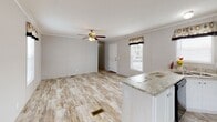 Located at 4056 E 133rd St in Chicago, IL, this single-floor home offers a practical and well-appointed layout designed for comfortable everyday living. The interior is unified by warm wood-look luxury vinyl flooring that runs throughout every room, complemented by neutral gray panel walls and crisp white crown molding trim.

The open living area is anchored by a ceiling fan with light fixture and features multiple windows with decorative valances, allowing natural light to fill the space. A granite-topped kitchen peninsula separates the living area from the kitchen, which is outfitted with white cabinetry, granite-style countertops, a stainless steel sink, and black Whirlpool appliances including a gas range, over-the-range microwave, and refrigerator. A door from the kitchen leads directly to an exterior entry.

The home includes multiple bedrooms, each with neutral-toned panel walls, individual windows with blinds, and the same consistent wood-look flooring. Two bathrooms serve the home: one features a double-sink vanity with granite countertops, white cabinetry, and a wall-mounted storage cabinet; the second offers a single-sink vanity and a full tub-shower combination. Both bathrooms maintain a clean, bright aesthetic with light-toned finishes throughout.