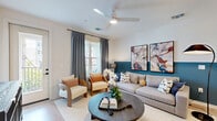 Located in Orlando's Lake Nona area, this well-appointed 2-bedroom, 2-bathroom residence offers a thoughtfully designed single-floor layout. The open-concept living area makes a strong first impression, featuring light hardwood-style flooring, a ceiling fan, and a bold teal accent wall adorned with curated artwork. Natural light pours in through large windows dressed with elegant drape panels, while a private entry door adds convenience. The kitchen is a standout feature, showcasing crisp white shaker cabinetry, quartz countertops, stainless steel appliances, a subway tile backsplash, and a central island with bar seating illuminated by sleek pendant lighting. The primary bedroom is generously sized, offering a ceiling fan, patterned drapes, and ample room for a full furniture arrangement. The primary bathroom impresses with a long double-vanity, large backlit mirror, white cabinetry with matte black hardware, and a glass-enclosed walk-in shower. The second bedroom features a soft blue accent wall, ceiling fan, and bright windows with outdoor views. Its adjoining bathroom includes a tub-shower combo with tile surround and a single vanity with matching finishes. Two closets provide practical storage throughout the residence.