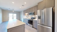 Located in Avondale, Arizona, this thoughtfully designed 2-bedroom, 1-bathroom single-floor residence offers a clean, contemporary aesthetic throughout. The kitchen is a standout feature, showcasing taupe shaker-style cabinetry with under-cabinet lighting, a crisp white quartz island, subway tile backsplash, and a full suite of stainless steel appliances including a French door refrigerator, electric range, over-the-range microwave, and dishwasher. Light wood-look flooring flows through the main living areas, enhancing the bright and airy atmosphere complemented by recessed lighting. The living area connects seamlessly to a private balcony through a full-width sliding glass door, offering outdoor views and natural light. The spacious primary bedroom features a ceiling fan and its own sliding glass door access to the balcony, while the secondary bedroom is finished with wood-look flooring and a ceiling fan. A well-organized walk-in closet with built-in shelving and hanging rods provides ample storage. The bathroom is finished with a dark vanity, white quartz countertop, and a backlit LED mirror. Neutral tones and modern finishes throughout create a cohesive, move-in-ready environment.