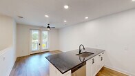 Located in Huntersville, NC, this two-story residence offers a thoughtfully designed layout spread across two levels. The ground floor houses a private garage with an automatic opener, providing secure and convenient parking along with additional storage space. A dedicated entrance and staircase connect seamlessly to the main living level above.

The upper floor comprises the primary living spaces, characterized by clean white walls, neutral tones, and an open, airy ambiance throughout. The generously sized bedroom features soft carpeted flooring, a ceiling fan with integrated lighting, and large windows that invite ample natural light and offer views of the surrounding greenery. An adjacent walk-in closet provides well-organized shelving for generous storage.

The bathroom is well-appointed with a tiled shower-tub combination, a white vanity with dark stone countertops, and matte black hardware accents that add a modern touch. Light wood-look flooring and a window complete the bright, clean aesthetic.

A standout feature of this residence is the private balcony, which overlooks lush mature trees and the well-maintained community grounds, offering a peaceful outdoor retreat. The modern farmhouse-inspired exterior of the surrounding community adds to the overall curb appeal. This residence combines functional design with comfortable living in a welcoming Huntersville community.