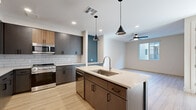 Located at 151 W High Country Trail in Flagstaff, AZ, this well-designed one-bedroom, one-bathroom unit offers a thoughtful layout with modern finishes throughout. The open-concept kitchen serves as the heart of the home, featuring a striking teal-accented island with a stainless steel undermount sink, two-tone cabinetry in dark gray and warm wood tones, white subway tile backsplash, stainless steel appliances including a gas range, microwave, dishwasher, and French door refrigerator, all illuminated by stylish pendant lighting and recessed fixtures. Light wood-tone flooring extends seamlessly into the living area, which is equipped with a ceiling fan and benefits from natural light through a large window. The bedroom is carpeted for comfort, includes a ceiling fan, a dedicated closet, and windows that frame views of the surrounding landscape and neighboring architecture. The bathroom features a tub-shower combo with clean white tile surround, a warm wood vanity with a light countertop, and bold navy accent walls that add a modern touch. The overall aesthetic is clean, contemporary, and cohesive, making this Flagstaff residence a polished and functional living space.