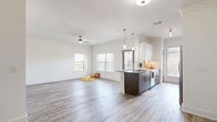 This thoughtfully designed single-story residence offers three bedrooms, two bathrooms, and a generous open-concept layout that maximizes both functionality and comfort. The combined kitchen and living area serves as the heart of the home, featuring light hardwood-style flooring, crown molding, and a ceiling fan that enhance the bright, airy atmosphere. Multiple windows allow natural light to fill the space, creating a welcoming ambiance throughout.

The kitchen is a standout feature, equipped with white upper cabinetry, dark wood lower cabinets, granite countertops, stainless steel appliances, and a central island with a built-in sink and pendant lighting overhead — ideal for both cooking and casual dining.

The bedrooms are carpeted for comfort, each with a ceiling fan and windows providing natural light and outdoor views. The primary bedroom offers a notably spacious layout with dedicated closet space. The bathrooms feature wood-toned vanities with granite countertops and wood-look tile flooring, maintaining a consistent design aesthetic throughout the home.

A dedicated laundry room with a full-size washer and dryer adds everyday convenience. Two hallways connect the living areas to the bedrooms, and three closets — including a carpeted walk-in — provide ample storage. The clean, neutral palette throughout gives the space a modern, move-in-ready appeal.