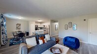 Located at 7266 Lockwood Ln in Indianapolis, Indiana, this single-story 2-bedroom, 2-bathroom home offers a thoughtfully designed open-concept layout. The combined living room and kitchen area serves as the heart of the home, featuring durable wood-look flooring, neutral walls, and a textured ceiling throughout. The living room is bright and welcoming, with a sliding glass door that opens to an outdoor deck, allowing natural light to fill the space.

The kitchen is well-equipped with white shaker-style cabinetry, a grey subway tile backsplash, stainless steel appliances including a refrigerator, range, microwave, and dishwasher, and a central island with a white countertop that provides both prep space and bar seating. A dedicated dining area sits adjacent to the kitchen, making the open layout ideal for everyday living and entertaining.

The primary bedroom offers a comfortable retreat with a natural light-filled window, wood-look flooring, a walk-in closet, and direct access to a private en-suite bathroom. The en-suite features a glass-enclosed walk-in shower and white vanity cabinetry. A second bedroom and additional full bathroom serve guests or household members. A hallway connects the private spaces efficiently, completing this functional and modern single-floor home.