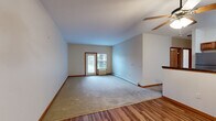 This single-floor residence offers a practical and comfortable layout, encompassing two bedrooms, two bathrooms, a combined kitchen and living area, and a dedicated closet. The open living room features a mix of hardwood-style flooring and carpet, a ceiling fan, and a window that allows natural light to fill the space, creating a bright and welcoming atmosphere. Baseboard heating runs throughout, ensuring efficient climate control across all rooms.

The galley-style kitchen is well-equipped with warm oak cabinetry, dark granite-style countertops, and a full suite of stainless steel appliances including a refrigerator, electric range, built-in microwave, and dishwasher. Wood-look plank flooring adds a clean, cohesive finish to the cooking space, which flows naturally toward the living area.

The primary bedroom offers a comfortable footprint with plush carpeting, a window with exterior views, and baseboard heating. The second bedroom is similarly carpeted and bright, with a large window providing natural light. A hallway connects the rooms, featuring rich wood-paneled interior doors that add a touch of warmth and character throughout. With its functional layout, classic finishes, and thoughtful design, this residence provides a comfortable and inviting living environment.