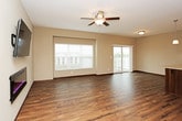 This multi-story home is designed with functionality and comfort in mind, offering thoughtfully laid-out spaces across three floors. The main living area is open and inviting, featuring rich hardwood-style flooring, a ceiling fan, and large windows that allow generous natural light to fill the room. A sliding glass door provides direct access to the outdoors. The kitchen is well-equipped, showcasing rich dark wood cabinetry, light granite countertops, stainless steel appliances including a range and over-the-range microwave, and pendant lighting that adds a polished touch. A breakfast bar connects the kitchen to the dining and living areas, enhancing the open-concept flow. The bedrooms are generously sized with plush carpeting, ceiling fans, and ample natural light from multiple windows. The primary bedroom includes a walk-in closet with wire shelving and a private en-suite bathroom. The bathrooms throughout feature light tile flooring, dark wood vanities with granite-style countertops, and tub-shower combinations with chrome fixtures. A dedicated laundry room accommodates a full-size washer and dryer, complemented by additional cabinetry and wire shelving for storage. Warm neutral tones and consistent dark wood trim unify the design throughout the home.