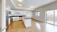 Located at 208 Woolwich St S in Breslau, Ontario, this well-appointed one-bedroom, one-bathroom unit offers a thoughtfully designed layout with modern finishes throughout. Light oak laminate flooring runs continuously across all rooms, complementing the neutral grey walls and crisp white trim.

The open-concept kitchen and living/dining area forms the heart of the unit. The kitchen is outfitted with white shaker-style cabinetry, dark granite countertops, a subway tile backsplash, and a full suite of stainless steel appliances including a refrigerator, stove, and built-in microwave. A central island with matching dark granite provides additional prep space and casual seating. The adjoining living and dining area is bright, with a window offering outdoor views and access to a private balcony.

The bedroom is a comfortable size, featuring a large double-door closet with panelled doors, a window with a roller blind, and a tray ceiling detail that adds architectural interest. A hallway connecting the main living area to the bedroom also provides access to two closets and the in-suite laundry.

The bathroom features a soaker tub and shower combo with full white subway tile surround and chrome fixtures, paired with light flooring for a clean, contemporary finish. The entrance provides a practical transition into the unit, completing a functional and modern floor plan.