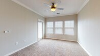 Located on S Lone Star Ave in New Braunfels, Texas, this single-story home offers a well-designed layout with a seamless blend of comfort and functionality. The open-concept living and dining area features plush wall-to-wall carpeting, crown molding, and a ceiling fan, creating a warm and inviting atmosphere. Natural light filters in through multiple windows dressed with white horizontal blinds, brightening the neutral-toned interior.

The kitchen is a standout feature, boasting rich dark-stained cabinetry with sleek hardware, granite-style countertops, and black appliances including a refrigerator, electric range, built-in microwave, and a kitchen island with a sink. Wood-look flooring runs throughout the kitchen and connects it visually to the adjoining living space. A dedicated laundry room is conveniently accessible directly from the kitchen.

The bedrooms are generously sized, each with soft carpeting, ceiling fans, crown molding, and ample natural light from blinds-covered windows. One bedroom includes access to an exterior door. The bathroom is clean and functional, featuring a full tub-shower combo with white subway tile surround, wood-look flooring, and granite-style countertops complementing the dark vanity cabinetry.