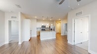 Located at 6047 Raleigh St in Orlando, Florida, this single-floor residence offers two bedrooms and two bathrooms within a well-designed, modern layout. The open-concept kitchen and living area serves as the heart of the home, featuring rich wood-look flooring, white shaker-style cabinetry, warm wood lower cabinets, granite countertops, a central island with pendant lighting, and a full suite of stainless steel appliances including a French door refrigerator, electric range, and built-in microwave. A tiled backsplash adds a refined finishing touch to the cooking space. Both bedrooms are carpeted for comfort and include ceiling fans, natural light from large windows with horizontal blinds, and views of the surrounding greenery. The spacious primary bedroom includes a dedicated walk-in closet outfitted with wire shelving for organized storage. The bathrooms are finished with granite-topped vanities, wood-toned cabinetry, brushed gold hardware, and full tub-shower combinations featuring vertically stacked white tile surrounds. A second closet provides additional storage convenience. The consistent use of neutral tones, modern fixtures, and quality materials throughout creates a clean, cohesive, and functional living environment.