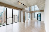 Located on the 28th floor of 1333 S Wabash Ave in Chicago's South Loop, this two-bedroom, five-bathroom residence spans two floors of thoughtfully designed living space. The unit's most striking feature is its expansive floor-to-ceiling windows, which flood the interior with natural light and frame breathtaking panoramic views of the Chicago skyline and surrounding cityscape.

The open-concept living area showcases light wood flooring and exposed concrete ceiling elements, lending an industrial-modern aesthetic throughout. The kitchen is well-appointed with dark walnut cabinetry, stainless steel appliances including a gas range, microwave, and refrigerator, a herringbone tile backsplash, and a sleek white quartz island with an undermount sink.

The bathrooms are finished with large-format light tile, frameless glass shower enclosures, dark wood vanities with white quartz countertops, and chrome fixtures. The primary bathroom features a dual vanity and a combined soaking tub and shower.

The bedrooms offer light wood flooring, large windows with urban views, and generous closet space. A glass partition wall in one bedroom adds a distinctive architectural detail. With four closets and two hallways connecting the dual-level layout, this residence provides both functional organization and a refined, contemporary living experience in the heart of Chicago.