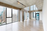 Located on the 28th floor of 1333 S Wabash Ave in Chicago's South Loop, this two-bedroom, five-bathroom residence spans two floors of thoughtfully designed living space. The unit's most striking feature is its expansive floor-to-ceiling windows, which flood the interior with natural light and frame breathtaking panoramic views of the Chicago skyline and surrounding cityscape.

The open-concept living area showcases light wood flooring and exposed concrete ceiling elements, lending an industrial-modern aesthetic throughout. The kitchen is well-appointed with dark walnut cabinetry, stainless steel appliances including a gas range, microwave, and refrigerator, a herringbone tile backsplash, and a sleek white quartz island with an undermount sink.

The bathrooms are finished with large-format light tile, frameless glass shower enclosures, dark wood vanities with white quartz countertops, and chrome fixtures. The primary bathroom features a dual vanity and a combined soaking tub and shower.

The bedrooms offer light wood flooring, large windows with urban views, and generous closet space. A glass partition wall in one bedroom adds a distinctive architectural detail. With four closets and two hallways connecting the dual-level layout, this residence provides both functional organization and a refined, contemporary living experience in the heart of Chicago.