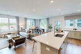 This thoughtfully designed single-floor residence offers two bedrooms and two bathrooms within a generously sized, open-concept layout. Light hardwood flooring flows throughout the main living areas, creating a cohesive and inviting atmosphere. The living room is bright and spacious, anchored by large windows that frame outdoor views and fill the room with natural light, complemented by recessed lighting overhead. Adjacent to the living room, the dining area features expansive windows with lush outdoor views, making it an ideal space for entertaining.

The kitchen is a standout feature, equipped with soft gray cabinetry, white quartz countertops, stainless steel appliances, subway tile backsplash, and a central island with bar seating. A built-in wine rack adds a refined touch.

The primary bedroom is generously proportioned, offering a sliding glass door to a private balcony with outdoor views, and soft sage-toned walls that create a calm retreat. The second bedroom is equally serene, with its own walk-in closet. Both bathrooms are finished with wood-toned vanities, white quartz countertops, and tile flooring, with the primary bath featuring a glass-enclosed walk-in shower. A hallway with an arched decorative mirror connects the bedrooms with elegance.