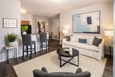 This thoughtfully designed 2-bedroom, 2-bathroom residence offers a functional and comfortable single-floor layout. The open-concept living, dining, and kitchen area forms the heart of the home, featuring durable wood-style flooring throughout the main spaces. The kitchen is equipped with warm honey-toned cabinetry, granite-style countertops, black appliances, and a pendant light above the adjacent dining area, which is framed by an elegant arched passageway. The living room is bright and welcoming, with a sliding glass door that opens to a private balcony, filling the space with natural light. A dedicated dining nook provides an intimate setting for meals. A hallway connects the main living area to the two bedrooms and bathrooms, offering a sense of separation and privacy. The primary bedroom is generously sized with plush carpet, a ceiling fan, natural light from multiple windows, and access to a full bathroom featuring a vanity with wood cabinetry and a tub-shower combo with a walk-in closet. The second bedroom mirrors the same comfortable, carpeted design with ample natural light from dual windows. Two closets and a convenient hallway complete this well-organized floor plan.