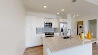 Located at 1011 Washington Blvd in Stamford, CT, this modern one-bedroom, one-bathroom residence delivers a clean, contemporary aesthetic across a thoughtfully designed single-floor layout. Light-toned hardwood-style flooring flows seamlessly throughout, complementing the bright white walls and creating a cohesive, airy atmosphere.

The open-concept kitchen is a standout feature, outfitted with white flat-panel cabinetry, granite countertops, a subway tile backsplash, and a full suite of stainless steel appliances including a range, built-in microwave, and french door refrigerator. A center island with an undermount sink adds both workspace and a natural gathering point.

The living area is bathed in natural light thanks to expansive floor-to-ceiling windows framed in dark metal, offering sweeping elevated views of the Stamford skyline and surrounding cityscape. The bedroom is generously proportioned, featuring its own access to a walk-in closet and direct connection to the main corridor.

The bathroom is finished with neutral large-format tile surrounding a soaking tub and shower combination, accented by chrome fixtures and recessed lighting. The overall design of this residence emphasizes modern simplicity, abundant natural light, and high-quality finishes, making it a refined urban living space in the heart of Stamford.