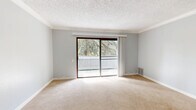 Located at 5959 Riverside Blvd in Sacramento, CA, this single-story, one-bedroom, two-bathroom residence offers a thoughtfully arranged floor plan with a comfortable and functional layout. Soft gray walls, crown molding, and textured ceilings carry consistently throughout the home, lending a cohesive and understated aesthetic.

The living room is a bright, open space anchored by a sliding glass door that leads to a private balcony overlooking lush, mature trees — filling the room with natural light and serene outdoor views. The adjacent dining area flows seamlessly into the kitchen, which features white cabinetry, light stone-look countertops with a breakfast bar, and a full suite of appliances including a range, microwave, and refrigerator, all set above warm hardwood-style flooring.

The spacious primary bedroom is a true retreat, complete with a ceiling fan, natural light from a window with blinds, and a full wall of mirrored sliding closet doors that enhance the sense of space. The two bathrooms include a combined bathroom and laundry room for added convenience, as well as a second full bath with a soaking tub and shower. Three closets throughout the home provide ample storage. Plush carpeting in the bedroom and living areas adds warmth and comfort to this well-appointed Sacramento residence.