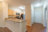 Located at The Bristol in Memphis, Tennessee's 38104 zip code, this single-floor unit offers a practical and comfortable layout with a neutral color palette throughout. The spacious living area is finished with plush wall-to-wall carpeting and includes a ceiling fan overhead. French doors provide natural light and connect the room to the exterior, enhancing the open feel of the space.

The kitchen is a functional highlight, featuring granite countertops that extend across a peninsula with an integrated sink, offering both prep space and a casual dining area. Light wood cabinetry provides ample storage, while stainless steel appliances — including a refrigerator and microwave — complement the black electric range. Hardwood-style flooring runs through the kitchen and extends into adjacent areas, with a window at the end bringing in natural light.

The bedrooms are carpeted and generously sized, each with windows fitted with blinds. Ceiling fans are present in select rooms. The bathrooms feature granite vanity tops, wood cabinetry, and tiled tub surrounds. A walk-in closet with built-in shelving and rod adds practical storage. The overall ambiance is clean, neutral, and move-in ready.