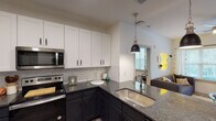 This single-floor residence in Seneca, SC offers a thoughtfully designed layout with modern finishes throughout. The kitchen is a standout feature, showcasing a two-tone cabinet design with crisp white upper cabinetry and dark lower cabinets, granite countertops, a classic subway tile backsplash, stainless steel appliances including a refrigerator, range, and built-in microwave, and a peninsula with a pendant light and undermount sink. Light wood-style flooring runs throughout, complementing the clean, contemporary aesthetic. The open sightline from the kitchen into the living area creates a connected, functional flow.

The living room is bright and welcoming, featuring a window and glass door that provide natural light and access to an outdoor area with views of surrounding greenery. Multiple bedrooms offer comfortable accommodations, each with windows, ceiling fans, and ample closet space. The bathrooms are finished with granite-top dark vanities, wood-style flooring, and include both tub/shower combinations and walk-in closets. Recessed lighting and modern fixtures are found throughout the home.

Overall, this residence presents a clean, modern interior with quality finishes, practical storage solutions, and a layout well-suited for everyday living in Seneca, South Carolina.
