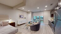 Located at 59 2nd Ave in Raritan, NJ, this thoughtfully designed single-floor residence offers a seamless blend of modern aesthetics and functional living. The open-concept layout connects the living, dining, and sleeping areas, creating an airy and cohesive environment throughout.

The living area is anchored by light hardwood-style flooring, recessed lighting, and a large window with a roller shade that floods the space with natural light and provides views of the surrounding greenery. A plush seating arrangement, glass coffee table, and elegant white sideboard with gold accents add refined character to the room.

The sleeping area is generously proportioned, featuring a full-sized bed with an upholstered headboard, a bedside chest, and ample closet space. The room maintains the same warm, neutral palette found throughout the residence.

The kitchen is well-appointed with rich dark cabinetry, stainless steel appliances including a gas range, microwave, refrigerator, and dishwasher, and clean white countertops. A window adjacent to the kitchen allows for additional natural light.

The bathroom features a full tub-shower combination with mosaic tile surround, a dark wood vanity with a white basin, a large mirror, and neutral tile flooring, completing this polished and practical space.