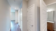 Located at 501 W Waugh St in Dalton, GA, this well-appointed 3-bedroom, 2-bathroom single-floor home offers a thoughtfully designed layout with modern finishes throughout. The open-concept kitchen and dining area serves as the heart of the home, showcasing warm wood-toned cabinetry, a subway tile backsplash, stainless steel appliances including a refrigerator, range, and microwave, and a central granite-topped island with a built-in sink and pendant lighting above. Hardwood-style flooring runs throughout the main living and kitchen areas, adding warmth and continuity to the space. The bedrooms are carpeted for comfort and feature large windows that invite natural light and offer views of the surrounding neighborhood. The primary bedroom includes a dedicated walk-in closet with wire shelving, providing practical storage. The bathrooms are finished with granite vanity tops, wood-toned cabinetry, and a subway-tiled tub-shower combination. A well-lit hallway connects the bedrooms and bathrooms, lined with paneled white doors and neutral gray walls. Recessed lighting and pendant fixtures add a contemporary touch throughout, while the clean, neutral color palette creates a cohesive and inviting ambiance across the entire home.