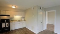 Located at 250 Sage Ave. in Mobile, Alabama, this single-floor space offers a practical and well-maintained layout designed for comfortable everyday living. The kitchen is outfitted with clean white cabinetry, a double-basin sink, and granite-look countertops that provide ample prep space. Under-cabinet lighting adds both functionality and a warm ambiance to the cooking area. The flooring transitions from rich hardwood-style planks in the kitchen and main living areas to carpet in the adjacent spaces, adding textural variety throughout the unit. Neutral, warm-toned walls create a bright and welcoming atmosphere, while the white trim and doors provide a crisp, finished look. The space is equipped with ceiling-mounted HVAC vents and a programmable thermostat, ensuring year-round climate control. A floor-level heating vent is also present, offering additional warmth during cooler months. The doors leading off the main area suggest thoughtfully separated living zones, providing privacy and organization within the single-floor footprint. Overall, the space presents a clean, move-in-ready environment with functional finishes suited to a variety of lifestyles.