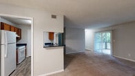 Located at 1038 South Hairston Road in Stone Mountain, GA, this single-floor, 3-bedroom, 2-bathroom home offers a functional and comfortable layout. The living room features plush carpeting, neutral-toned walls with chair rail molding, and a sliding glass door flanked by windows that fill the space with natural light and provide views of a private outdoor deck surrounded by mature trees. The dining area, accessible from the living room, is accented by a classic chandelier and matching chair rail detail. The kitchen features warm wood cabinetry, dark speckled granite-style countertops, a double basin sink, wood-look vinyl flooring, and a pass-through view into the dining area. The spacious primary bedroom offers carpeted floors, neutral walls, and windows with outdoor greenery views. Additional bedrooms share a similar design with carpet flooring and ample natural light. Both bathrooms include tub-shower combinations, with one bath featuring rich wood vanity cabinetry, a dark granite countertop, and wood-look flooring. A dedicated laundry room with wire shelving and utility hookups adds convenience. The home also includes a closet for additional storage.