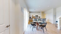This two-story home offers a well-appointed layout across two floors, combining modern design with practical functionality. The main floor features an open-concept kitchen, dining, and living area bathed in natural light from large windows. The kitchen is a standout, showcasing granite countertops, a spacious island with bar seating, white shaker cabinetry, subway tile backsplash, and stainless steel appliances. Light hardwood flooring flows throughout the main level, complementing the clean, bright aesthetic. A half bathroom on the main floor adds convenience for guests. The living room provides a comfortable, well-lit retreat with recessed lighting and a neutral color palette. Upstairs, the primary bedroom is generously sized, featuring plush carpeting, a ceiling fan, and recessed lighting. It is accompanied by a luxurious en-suite bathroom finished with large-format marble-look tile, a frameless glass walk-in shower, a sleek vanity with LED mirror, and ample space. A spacious walk-in closet with multi-tier shelving adds to the primary suite's appeal. A dedicated laundry room with full-size washer and dryer hookups offers added convenience. With three full bathrooms, two bedrooms, and a thoughtful floor plan, this home delivers a refined and comfortable living experience.