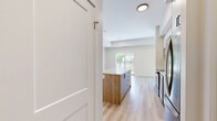 Located at 7219 Sharon Ave in Niagara Falls, Ontario, this thoughtfully designed two-bedroom, three-bathroom unit offers a clean, contemporary aesthetic throughout its efficiently utilized single-floor layout. Light-toned hardwood flooring flows seamlessly through the main living areas and bedrooms, contributing to a bright and cohesive atmosphere.

The kitchen is a standout feature, showcasing two-tone cabinetry with white upper cabinets and warm wood-finish lower cabinets, a classic subway tile backsplash, stainless steel appliances, and a central island with a white quartz countertop — ideal for both meal preparation and casual dining.

Each bedroom is finished with the same light hardwood flooring and neutral warm-beige walls. Large windows invite abundant natural light and offer views of the surrounding greenery and streetscape. The primary bedroom includes a built-in sliding closet, while both bedrooms benefit from a calm, airy ambiance.

The bathrooms are finished to a modern standard, featuring wood-grain vanity cabinetry, white quartz countertops, framed mirrors, and tiled shower enclosures with sleek glass doors and crisp white horizontal tile work.

A private outdoor area framed by black iron fencing provides a pleasant exterior space with open views of the mature tree-lined neighbourhood, completing this well-appointed and move-in-ready unit.