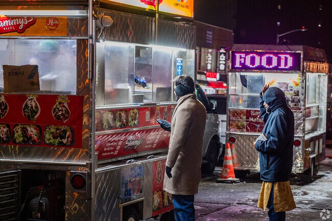 There are plenty of street food carts on the south west side of Woodside by the subway station.