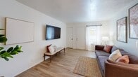 Located at 1200 N Perkins Rd in Stillwater, Oklahoma, this single-floor unit offers a thoughtfully designed layout with warm, contemporary finishes throughout. Light wood-tone flooring flows seamlessly across the entire space, creating a cohesive and inviting atmosphere.

The living area is bright and open, featuring a wall-mounted flat-screen TV, a cozy sofa, and a stylish bench seat, all anchored by a woven area rug. Natural light filters in through sheer curtains at the front window, enhancing the airy feel of the room.

The galley-style kitchen is efficiently designed with cream shaker cabinets, speckled quartz countertops, a deep single-basin sink with a matte black faucet, and stainless steel appliances including a refrigerator and electric range. Ample upper and lower cabinetry provides generous storage.

The bedroom is a comfortable and well-lit retreat with a large window that allows plenty of natural light. A closet provides convenient storage, and the room connects easily to the rest of the unit through a clean, well-proportioned hallway adorned with framed artwork.

The bathroom features a single vanity with white cabinetry, a round mirror, wall-mounted lighting, a medicine cabinet, and a shower-tub combination accented by a vibrant floral curtain, all set on the same warm wood-tone flooring found throughout the unit.